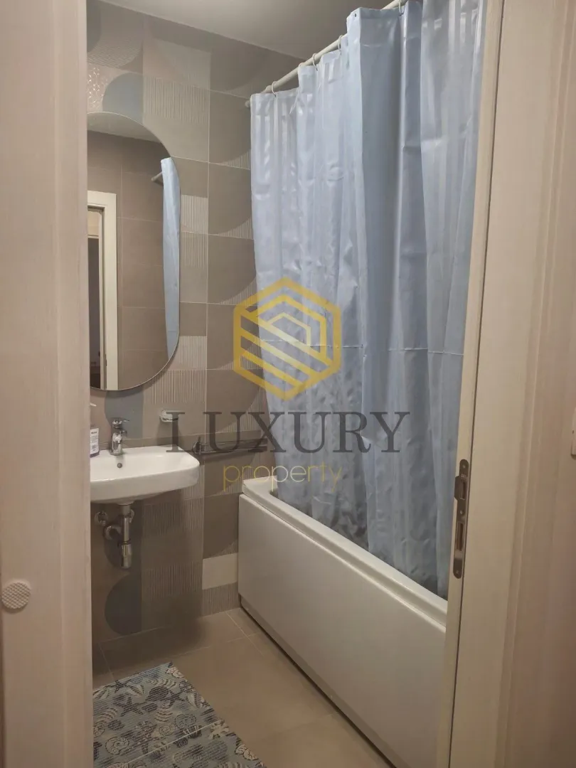 Small bathroom with a sink, mirror, and bathtub with a curtain.