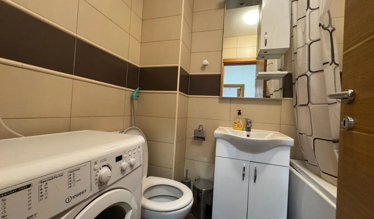 Small bathroom with a washbasin, toilet, washing machine, and bathtub.