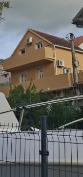 Pogled na spoljašnjost kuće sa balkonom i fasadom žute boje. - image 13