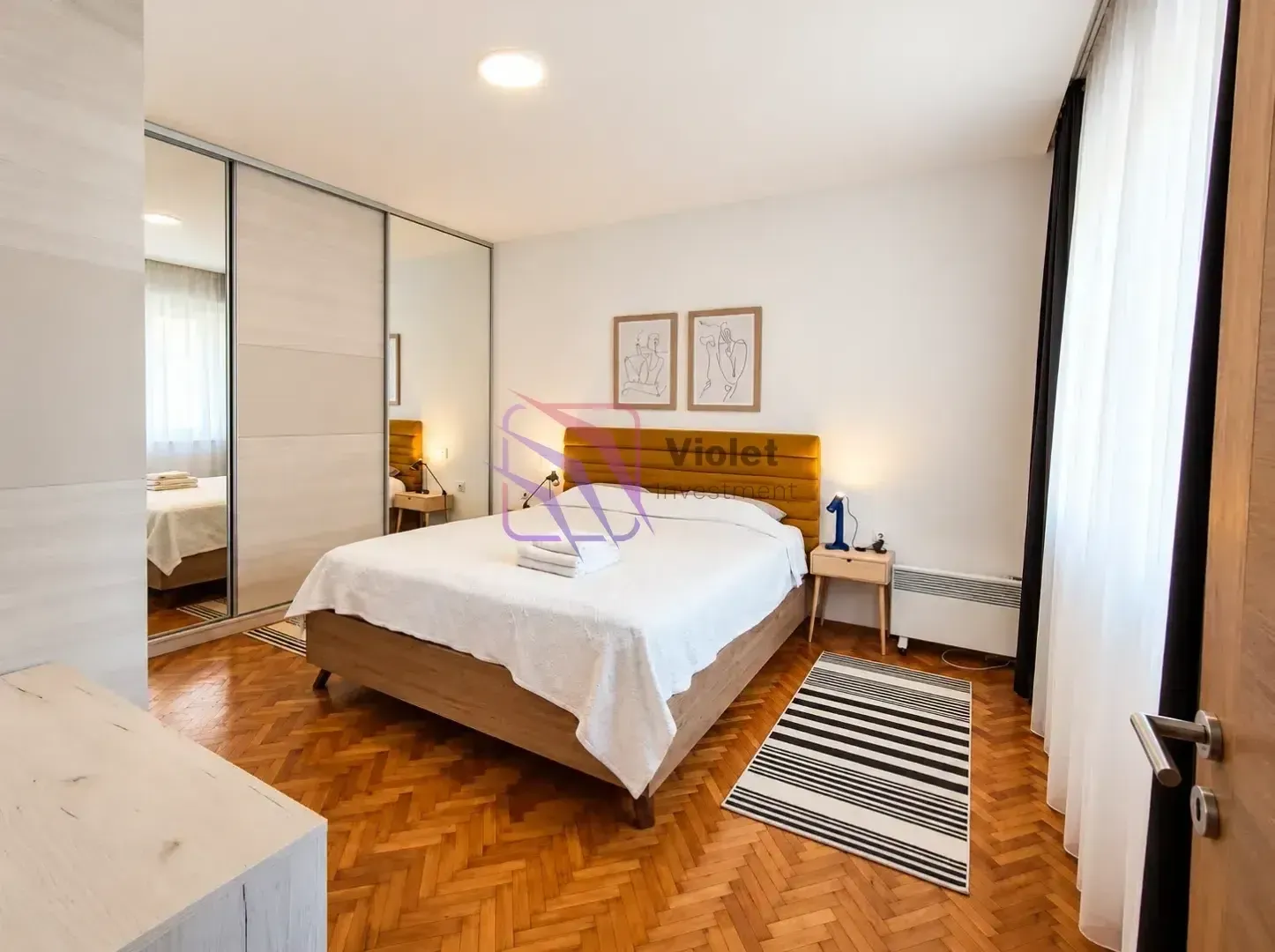 Furnished bedroom with a double bed and a mirrored built-in wardrobe.