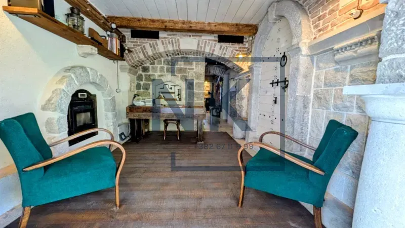 Living room with stone walls, fireplace, and green armchairs.