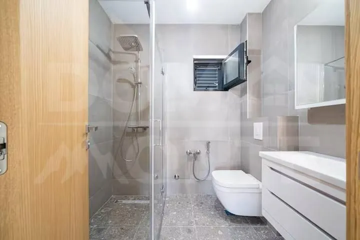 Moderno opremljeno kupatilo sa tuš kabinom i bijelim sanitarijama.