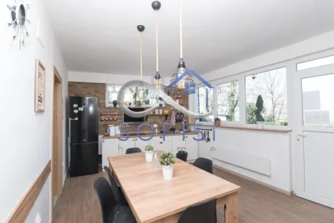 Kitchen with dining area equipped with a wooden table and a black refrigerator. - image 2
