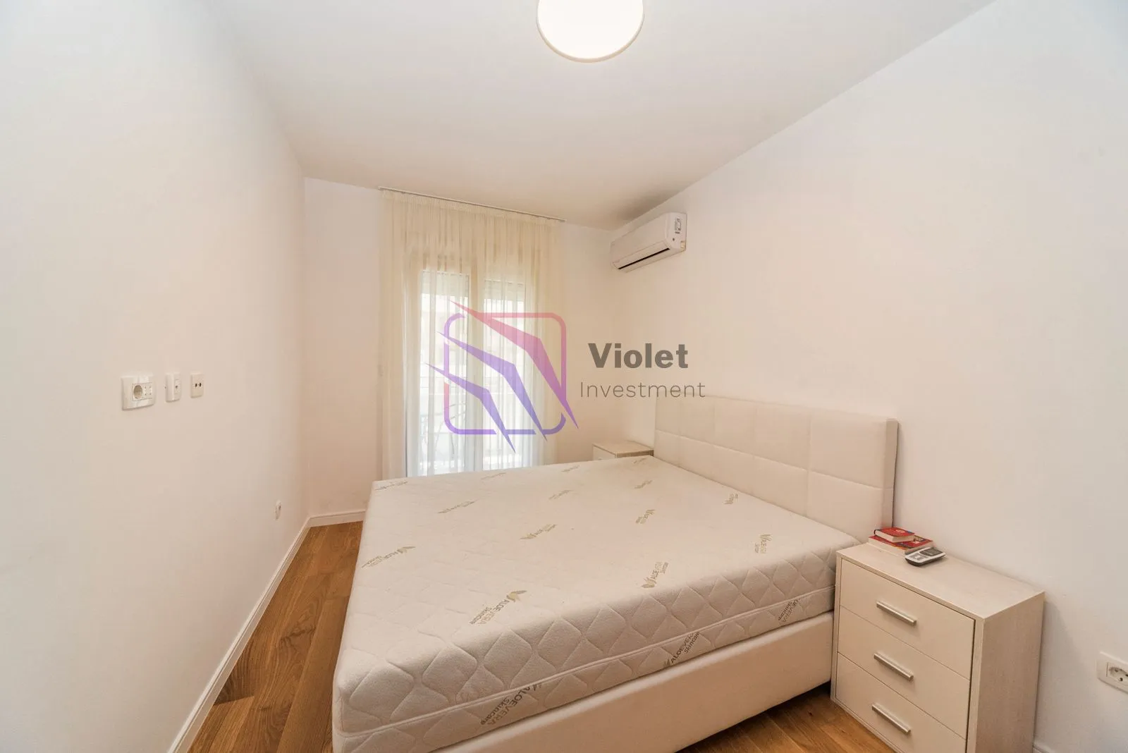 Smaller bedroom with a double bed, nightstand, and air conditioning unit.