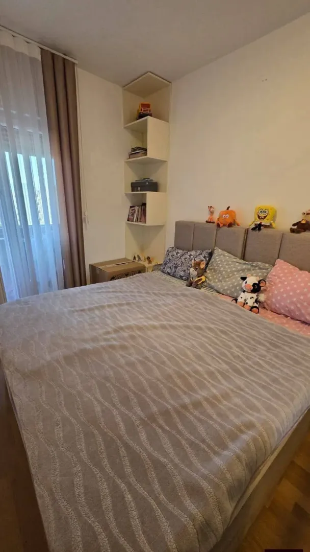 Namještena spavaća soba sa bračnim krevetom.