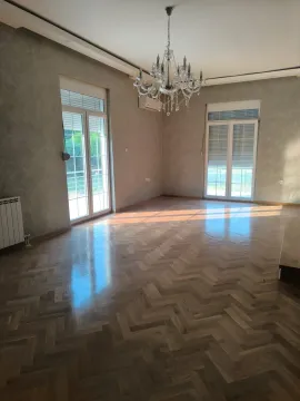 Empty living room with parquet flooring, a chandelier, and two balcony doors. - image 6