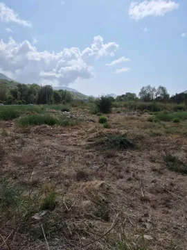 Pogled na zemljište sa niskim rastinjem i okolnim brdima u pozadini. - image 4