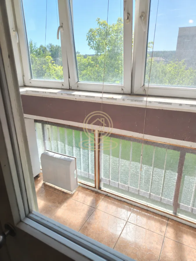 Pogled na zatvoreni balkon sa keramičkim pločicama i prozorima.