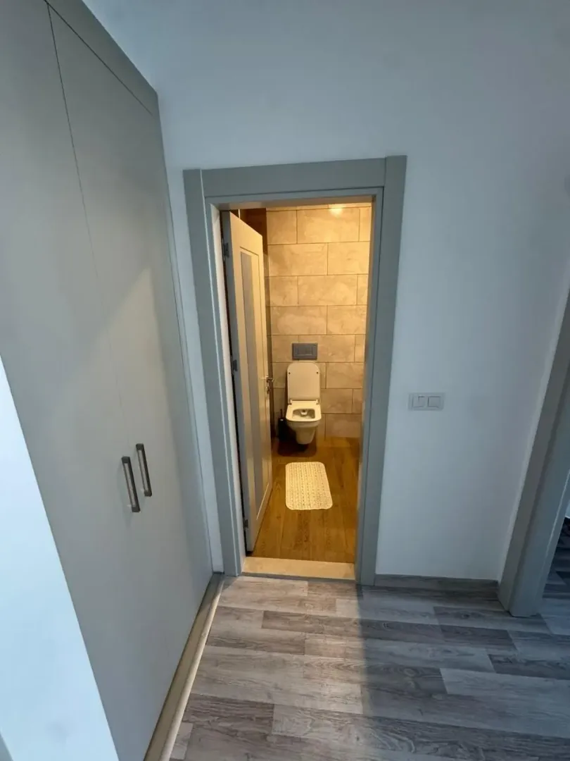 Pogled iz hodnika na kupatilo sa ugradnim ormarom i pločicama.