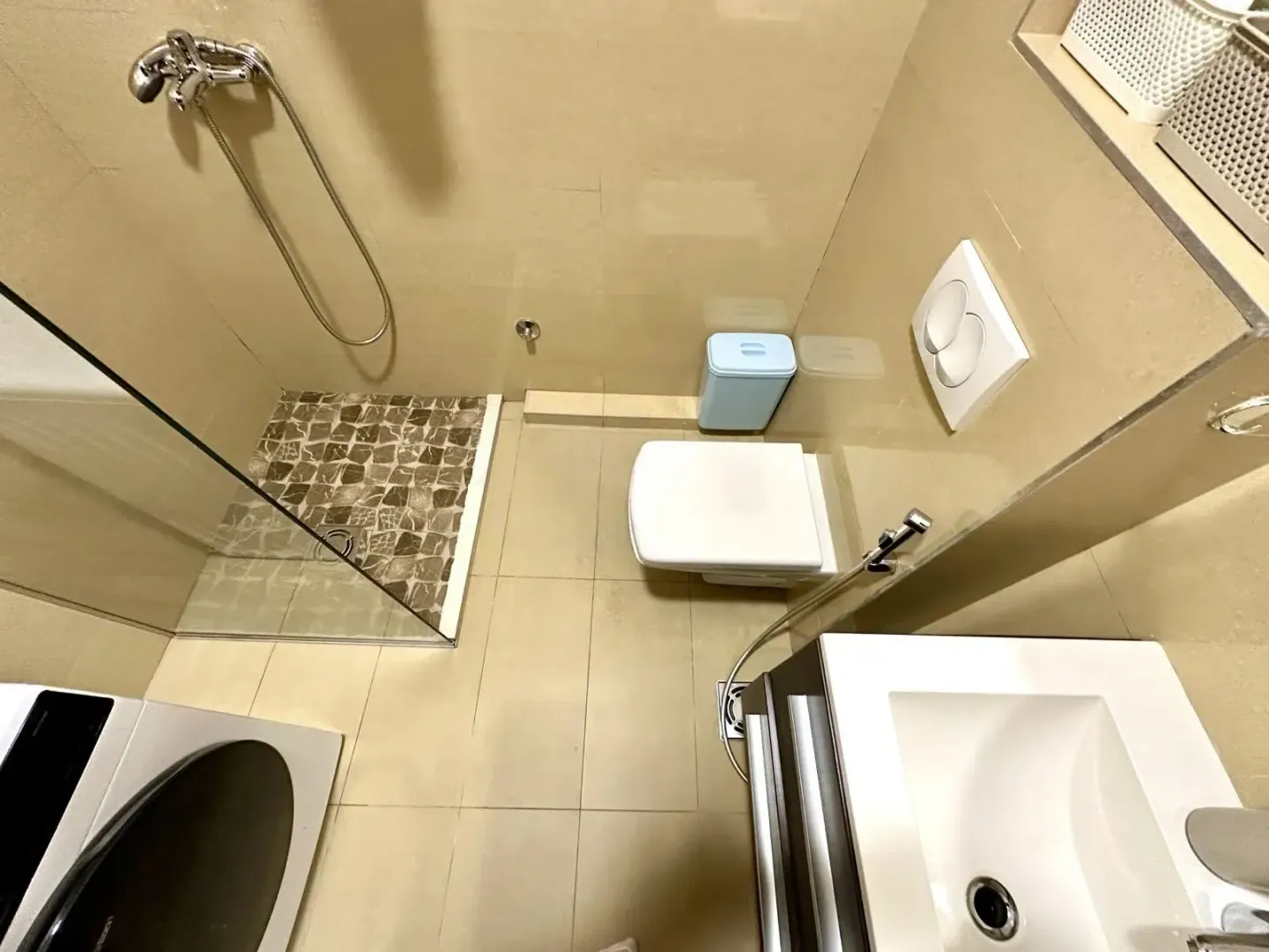 Manje kupatilo sa tuš kabinom, WC šoljom i umivaonikom.