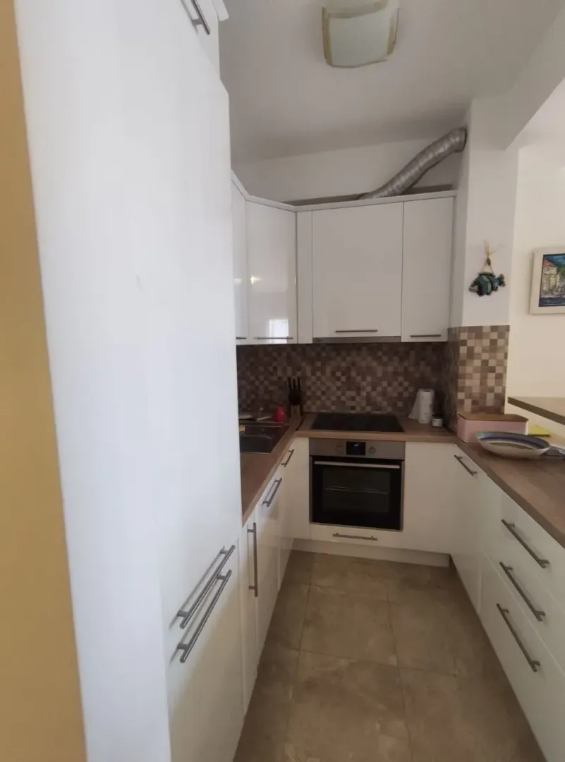 Manja bijela kuhinja sa ugradnom rernom i šporetom.