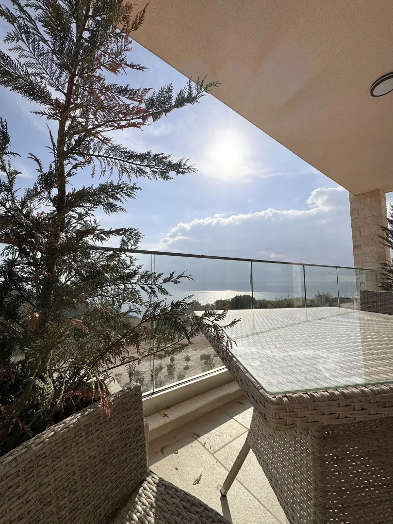 Furnished terrace with sea view and glass railing.