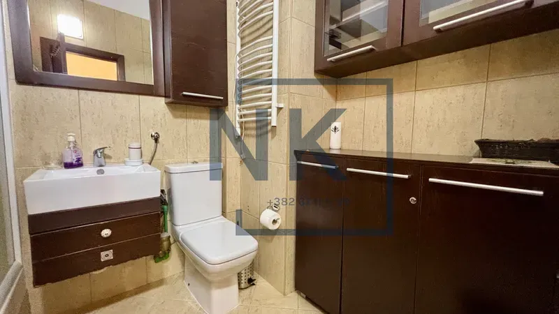 Kupatilo sa umivaonikom, WC šoljom i tamnim ormarićima.