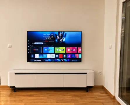 Living room with a wall-mounted TV and a white TV cabinet. - image 5