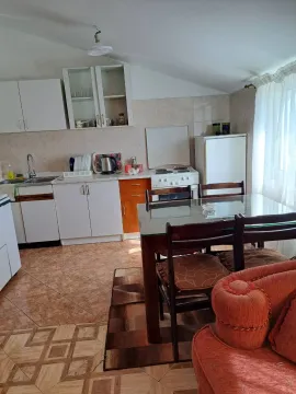 Kitchen equipped with white cabinets, a stove and a refrigerator, featuring a dining table and chairs. - image 4