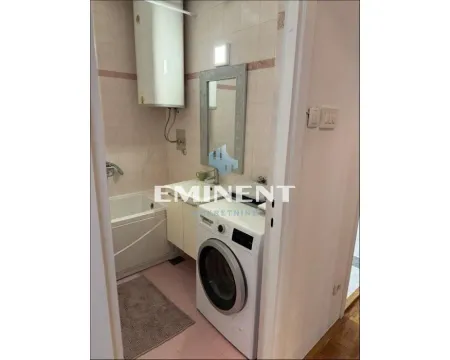Small bathroom with a bathtub, washbasin, and washing machine. - image 9