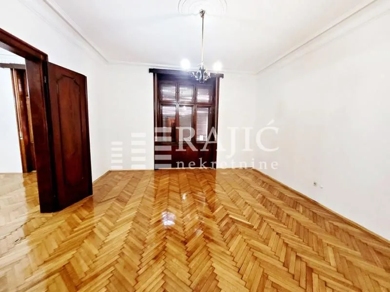 Empty room with hardwood flooring and wooden windows.