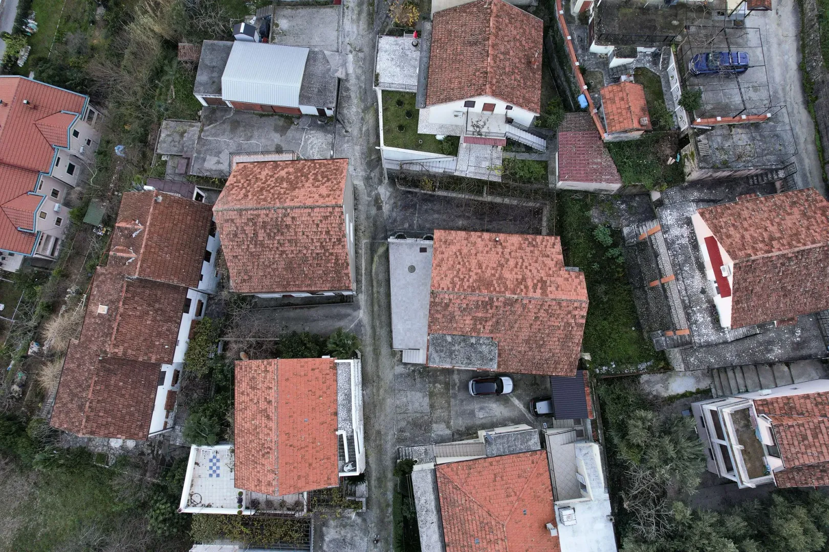 Pogled iz vazduha na okolne kuće i krovove sa crvenim crijepom.
