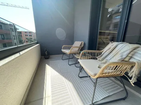 Covered balcony with seating furniture and a glass railing. - image 16
