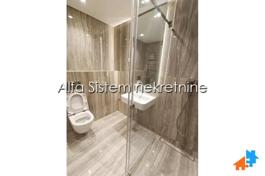 Moderno kupatilo obloženo keramičkim pločicama sa tuš kabinom i wc šoljom.