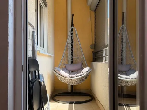 Smaller furnished balcony with a hanging chair. - image 11