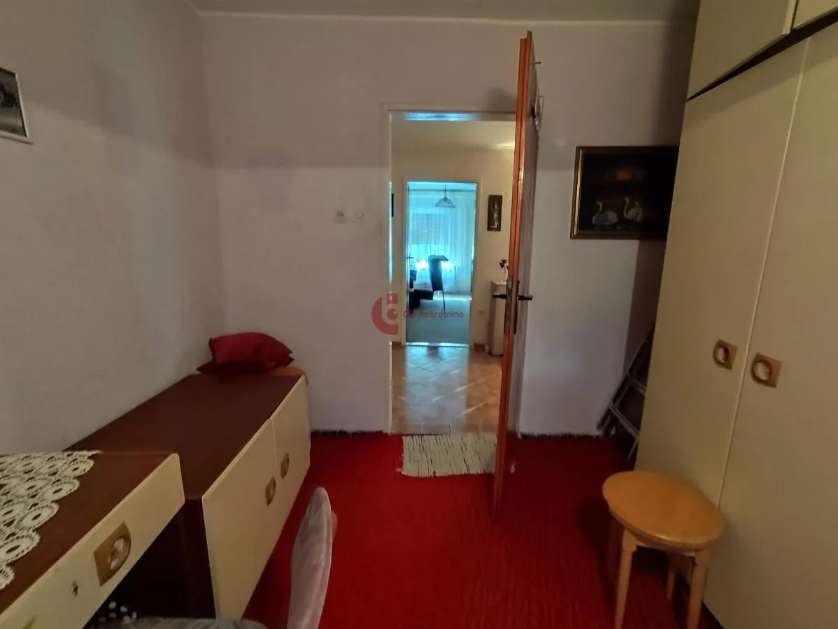 Furnished bedroom with a bed, wardrobe, and red carpet.