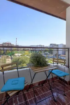 Small covered balcony with a table, two chairs, and a city view. - image 13