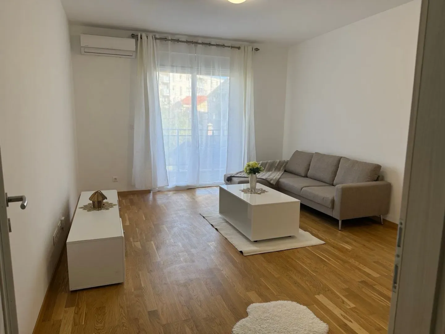 Svijetao i uredan dnevni boravak sa garniturom i izlazom na terasu.