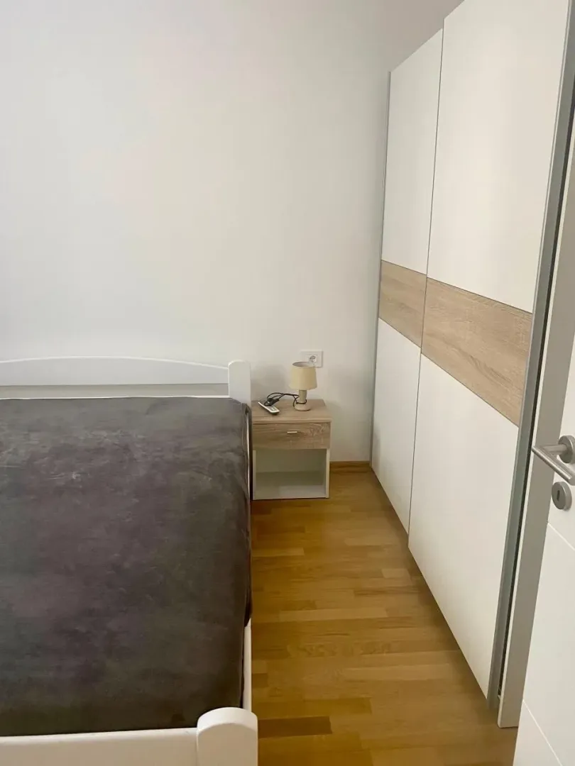 Furnished bedroom with a double bed, nightstand, and wardrobe.