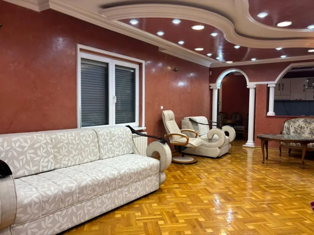 Spacious living room with a sofa set, parquet flooring, and a dropped ceiling.