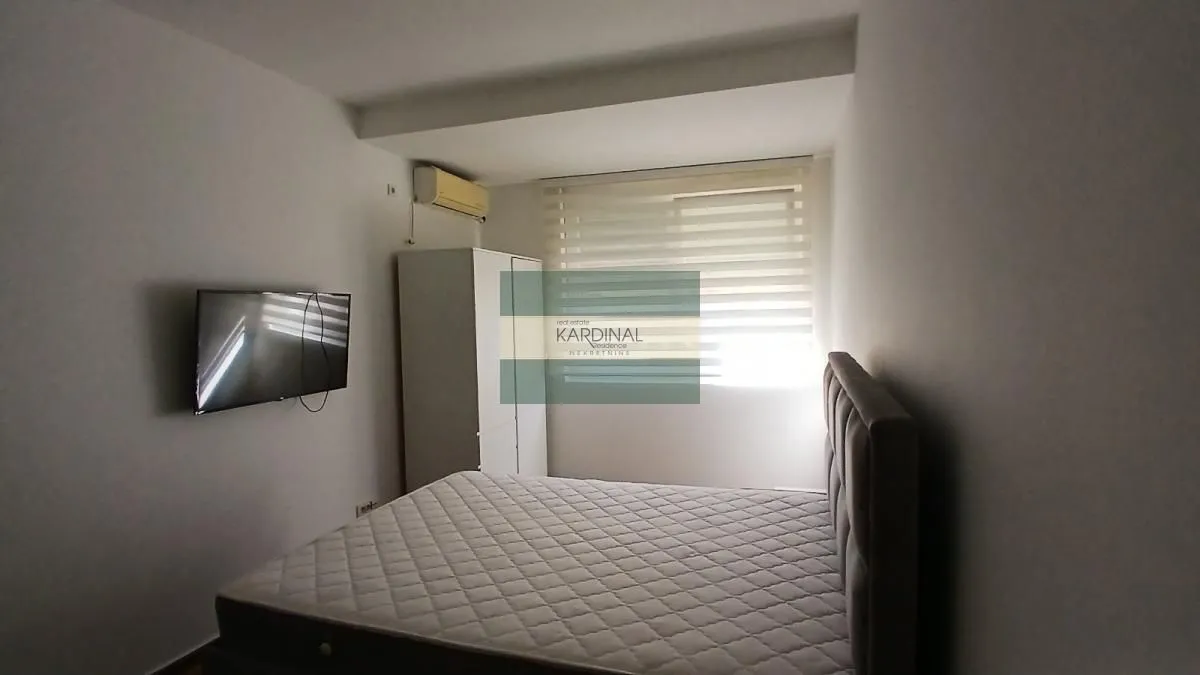 Nameštena spavaća soba sa bračnim krevetom, garderoberom i televizorom.