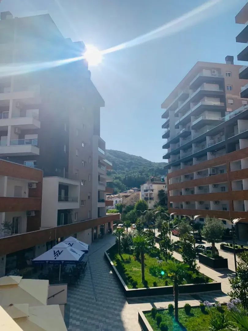 Eksterijer modernih stambenih zgrada sa uređenim dvorištem i zelenilom.