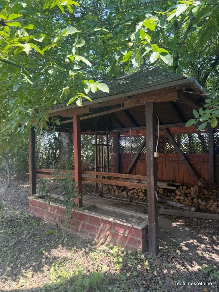Drvena sjenica u dvorištu sa složenim drvima za ogrev ispod.