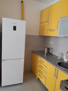 A simple kitchen featuring yellow cabinets and a white refrigerator. - image 16