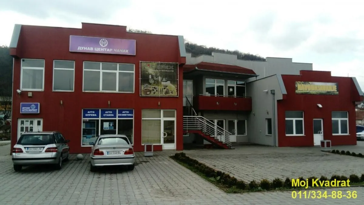 View of the exterior of a commercial building with parking and signs on the facade.