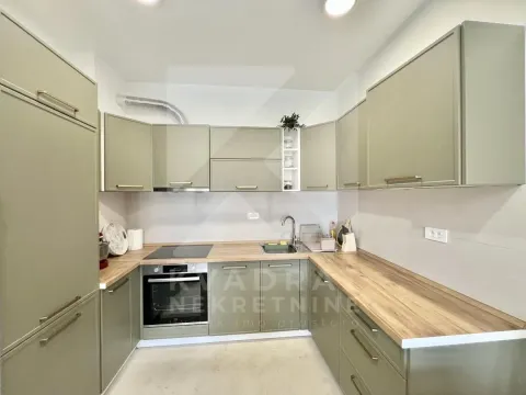 Modern kitchen with green cabinets and built-in appliances. - image 3