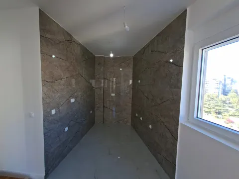 Empty kitchen with marble-effect ceramic tiles on the walls and a window. - image 9