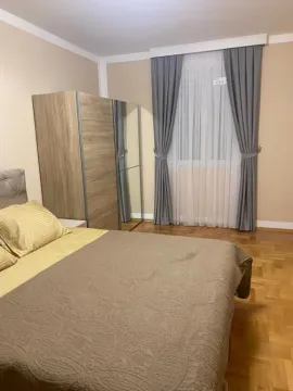 Namještena spavaća soba sa bračnim krevetom, plakarom i prozorom sa zavjesama. - image 18