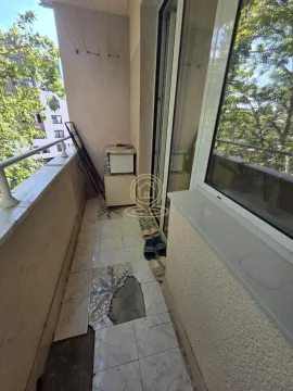 Uska terasa sa oštećenim podnim pločicama i pogledom na okolne zgrade i drveće. - image 16