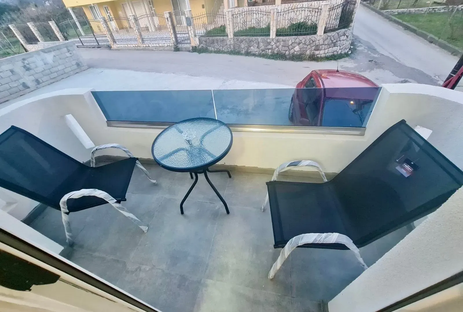 New chairs and small table on a balcony with a glass railing.