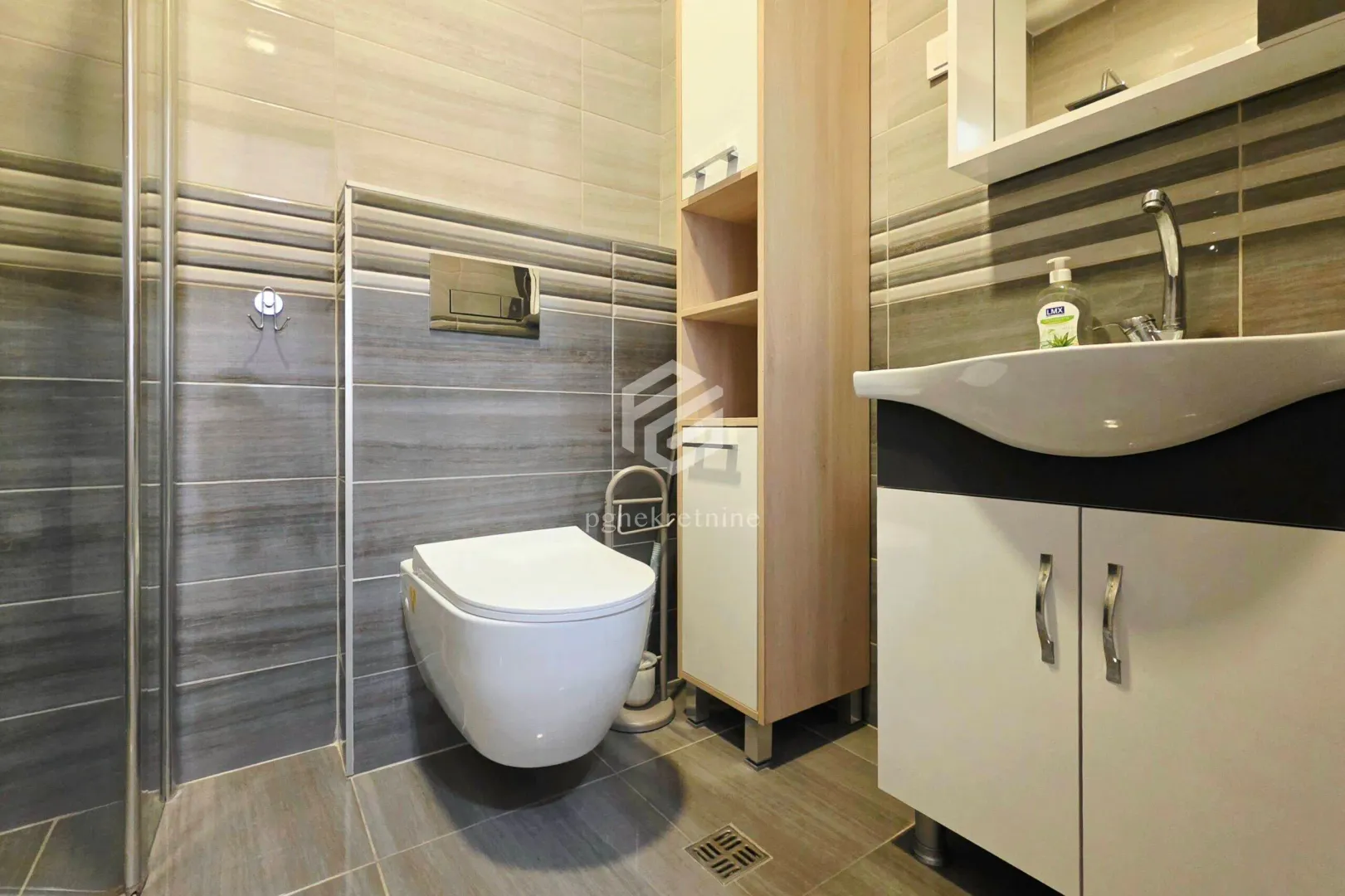 Bathroom equipped with a toilet, washbasin with cabinet, and a shower cabin.