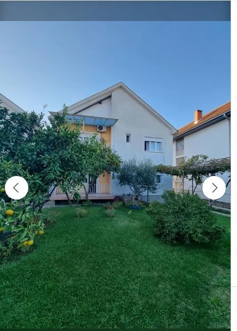 Dvorište kuće sa zelenim travnjakom i drvećem.