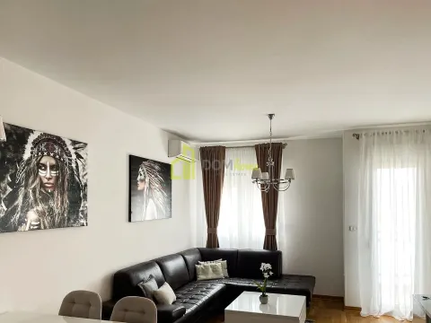 Dnevna soba sa ugaonom garniturom, trpezarijskim stolom i umjetničkim slikama na zidu. - image 6
