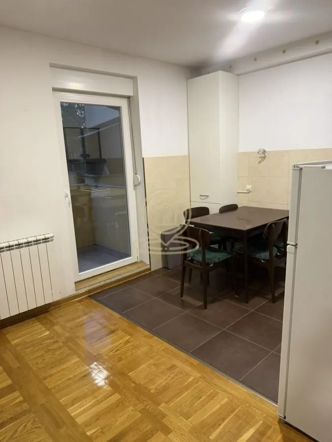 Kuhinja sa trpezarijskim stolom i izlazom na terasu.