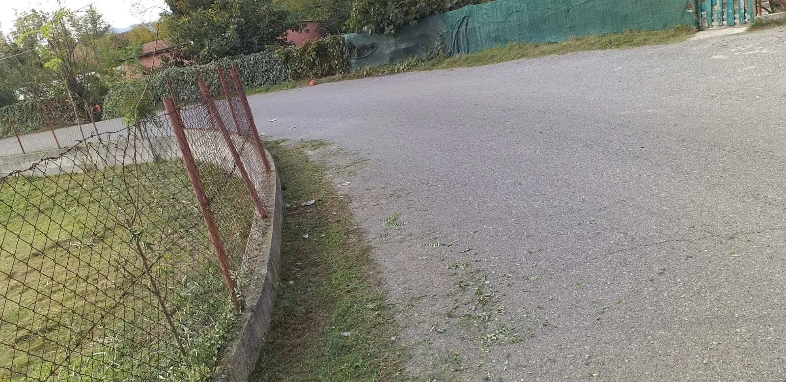 Asfaltirani prilazni put pored ograđenog placa.