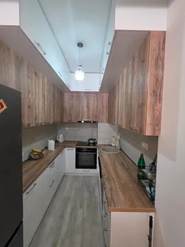 Narrow kitchen with wooden cabinets and built-in appliances. - image 4