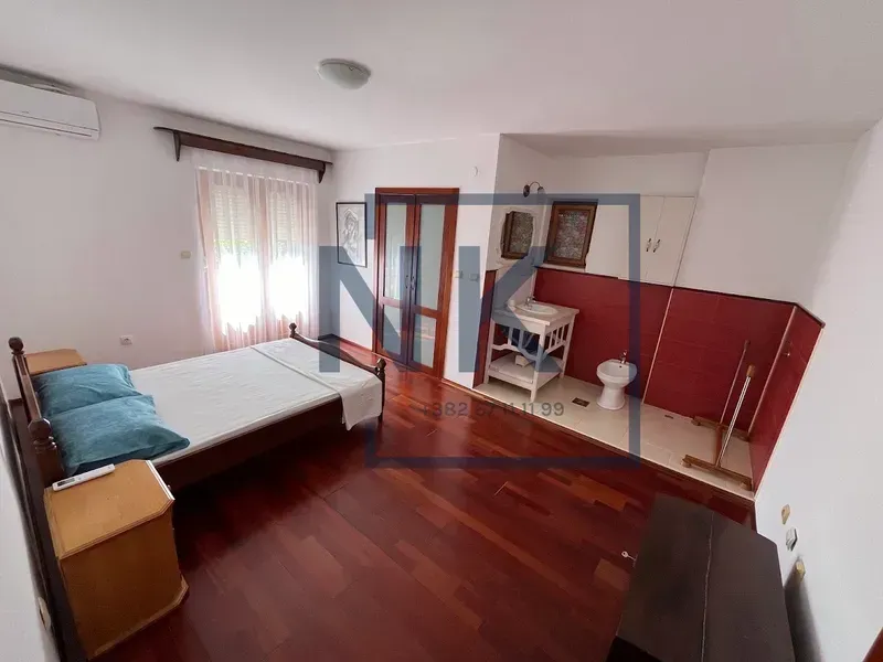 Spavaća soba sa bračnim krevetom i otvorenim kupatilom sa crvenim pločicama.
