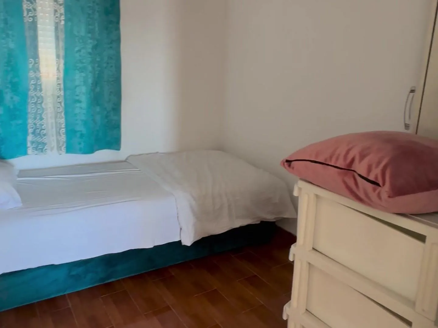 Small bedroom with a bed and a window with blue curtains.