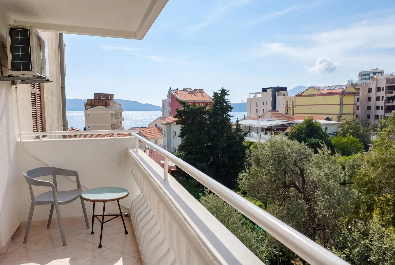 Manji namješteni balkon sa pogledom na more i okolne zgrade.