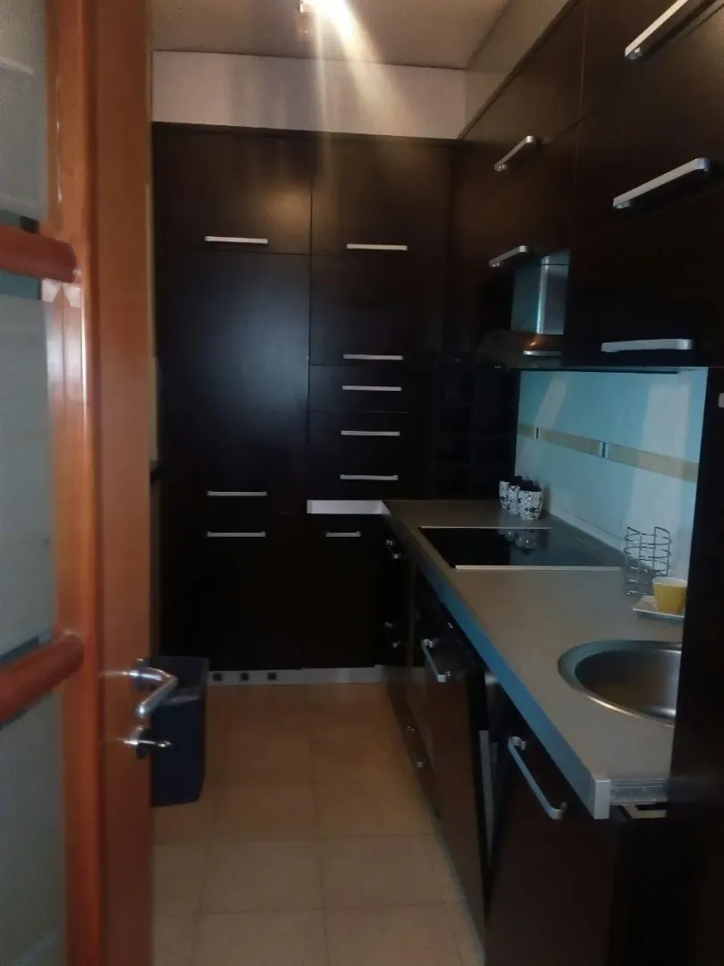 Narrow kitchen with dark cabinets and built-in appliances.